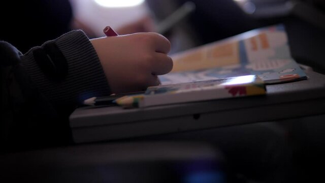 Close-up of a little boy drawing on an airplane during a flight. The child is having fun on the plane.