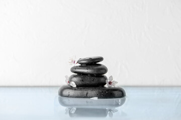 Black spa stones with flowers in water on white background