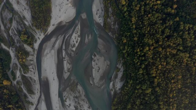 Aerial view of Laba river valley at dawn in autumn, Mostovskoy, Krasnodar Krai, Russia. Picturesque landscape, nature of Caucasus from drone. River flood, orange trees, stony coast snowy shore.