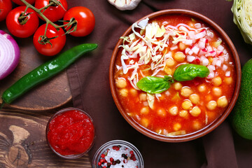 Tasty pozole soup and ingredients on wooden background