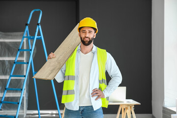Male builder with wooden planks in room