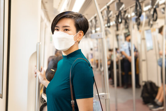 Beautiful Smart Looking Asian Woman Wear Disposable Face Mask On City Public Train Using Smartphone To Join Her Social Media While Travel To Office. Urban, New Normal, Lifestyle, Technology, Covid 19