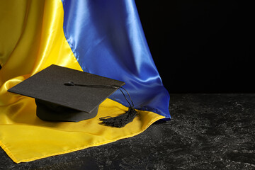 Graduation hat and flag of Ukraine on black background