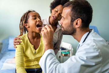 Young male pediatrician doctor examining child at office. Healthcare prevention exam people concept
