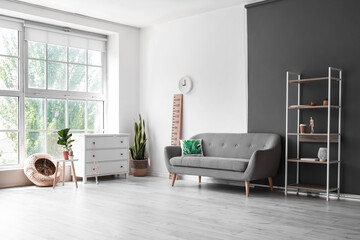 Fototapeta premium Interior of light living room with shelving unit, sofa and stadiometer