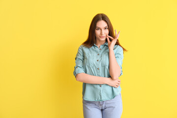 Young woman zipping her mouth on color background