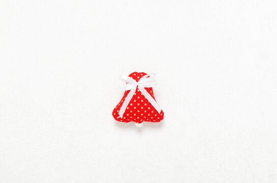 Handmade Christmas red fabric bell of  with white ribbon on white 
background.

