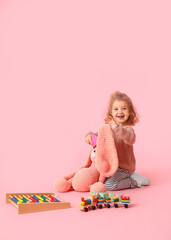 Cute baby girl with toys on color background