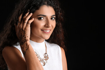 Beautiful Indian woman with henna tattoo on dark background