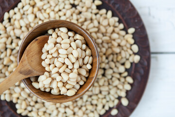 pine nut kernels in a clay plate, fresh pine nuts on a white background
