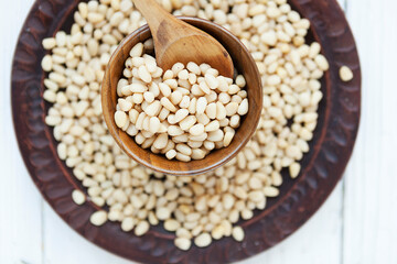 pine nut kernels in a clay plate, fresh pine nuts on a white background