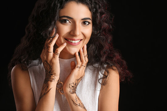 Beautiful Indian woman with henna tattoo on dark background