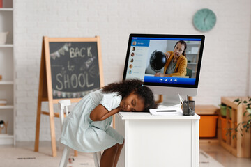 Little African-American girl sleeping at table instead of studying online at home
