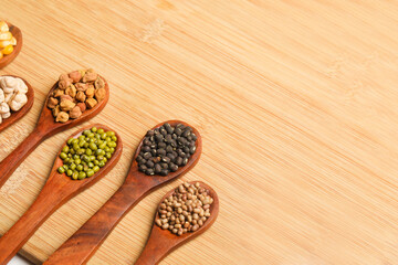 various dried types of bean and pea in wooden spoon.