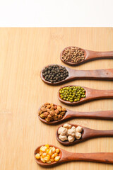 various dried types of bean and pea in wooden spoon.