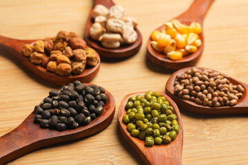 various dried types of bean and pea in wooden spoon.