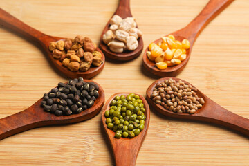 various dried types of bean and pea in wooden spoon.