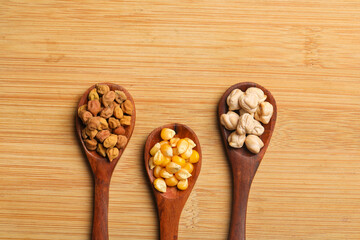 various dried types of bean and pea in wooden spoon.