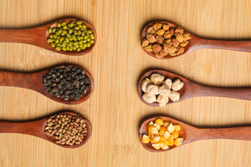 various dried types of bean and pea in wooden spoon.