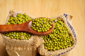 Green gram or mung bean in bag over wooden background.