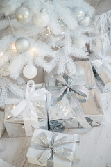 Decoration with Christmas toys and fir branches. Christmas balls in silver style and wrapped gifts