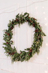 Decorations for the new year, a wreath of fir branches on the wall. Christmas decorative wreath in a cozy home