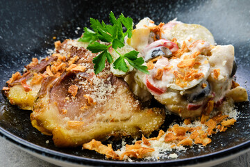 Closeup view of pickled cucumber with boiled potato and olives served with fried pork belly slices