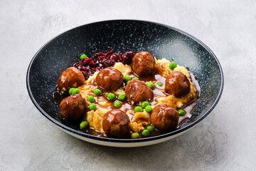 Meatballs with gravy served with mashed potato, green pea and cranberry jam