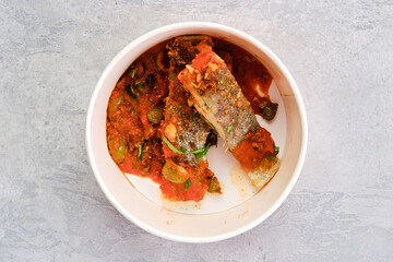 Top view of roasted zander served with steamed tomato, onion and olive sauce