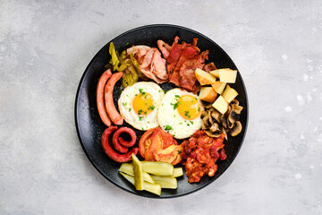Top view of fried egg, sausage, champignon, bacon, bean ragout, ham, cheddar, tomato and bell pepper
