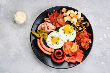 Top view of fried egg, sausage, champignon, bacon, bean ragout, ham, cheddar, tomato and bell pepper