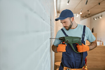 Bearded man drilling wall with hammer drill