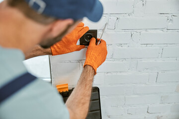 Man hands in work gloves repairing electrical wall socket