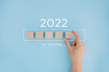 Female hand putting wooden cube for countdown to 2022. Loading year from 2021 to 2022. New year...