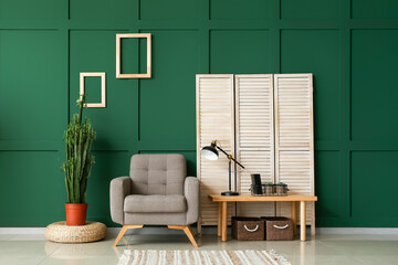 Interior of stylish room with armchair, green cactus and folding screen