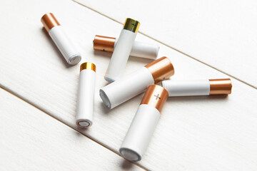 Alkaline batteries on white wooden background, closeup