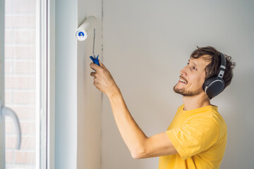 One male house painter worker painting and priming wall with painting roller. DIY