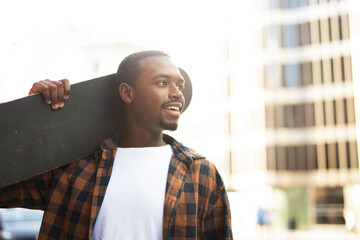 Happy african man with skateboard. Young fashion man with skateboard outdoors.