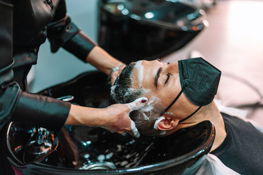Young man having salon hair wash wearing mask