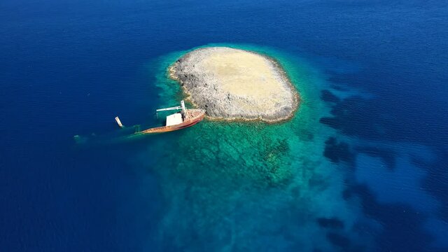 Aerial drone video of famous shipwreck of "Nordland" half sunk ship in islet of Prasonisi near Diakofti main port of Kithira island, Ionian, Greece