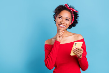 Photo of cute charming african lady dressed red off-shoulders shirt holding modern gadget looking empty space isolated blue color background