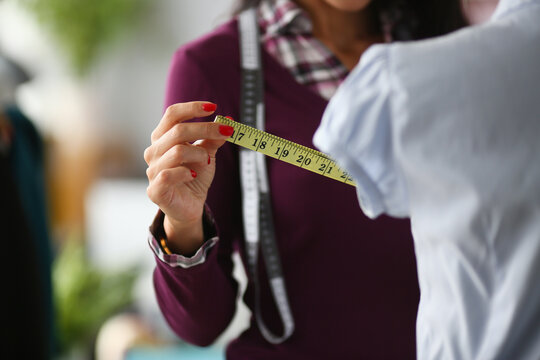 Woman fashion designer takes measurements with centimeter