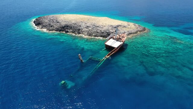 Aerial drone video of famous shipwreck of "Nordland" half sunk ship in islet of Prasonisi near Diakofti main port of Kithira island, Ionian, Greece