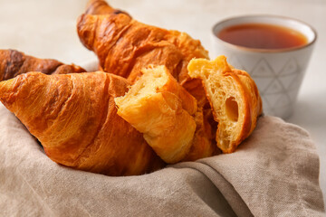 Basket with delicious croissants on white background, closeup