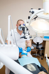 Fototapeta premium The dentist treats his patient's teeth with a microscope. The dentist treats the patient's mouth. Dental care