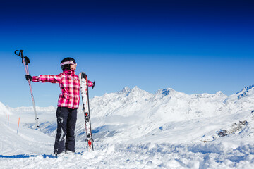 Fototapeta na wymiar Young happy girl in snowy mountains with skis enjoying winter time