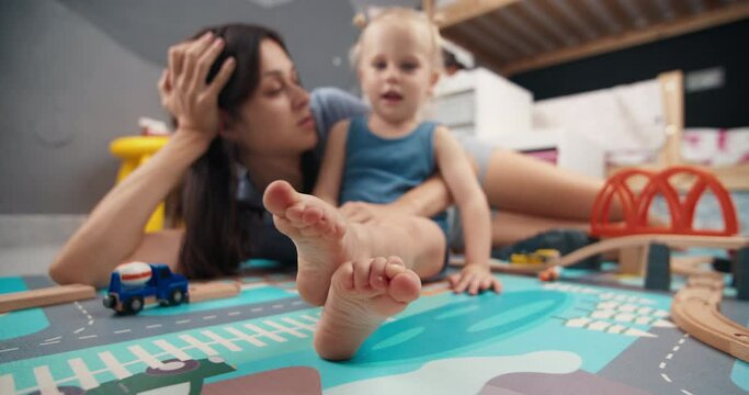 Happy young mother with cute daughter talking in child room. Concept of carefree childhood and family togetherness. Smiling mum enjoying bonding cuddling hugging spending time with funny kid at home