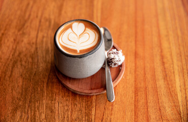 Trendy grey stylish cup of hot cappuccino with latte art on wooden table background. One cup for...