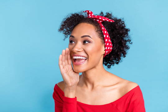 Photo of adorable funny african lady dressed red shirt arm mouth making announcement looking empty space isolated blue color background