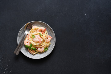 Spaghetti with shrimps, béchamel sauce and parmesan on a concrete black background. View from above. Menu. Recipe.